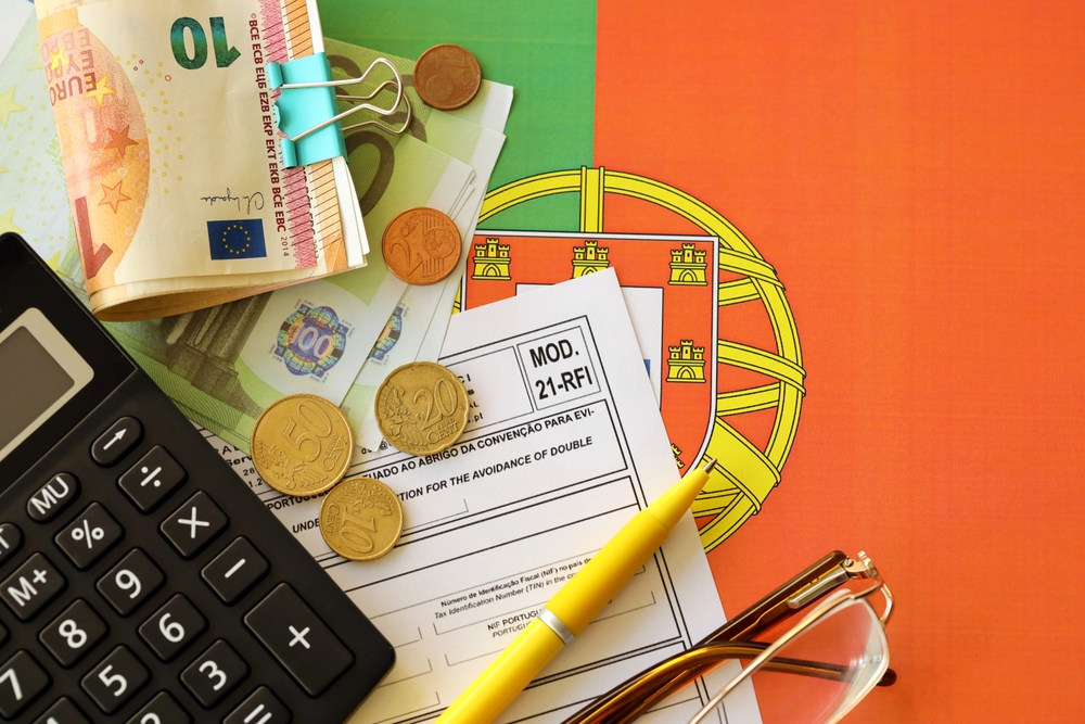 Calculator and Euro banknotes on a Portuguese tax form Mod 21-RFI with national flag background