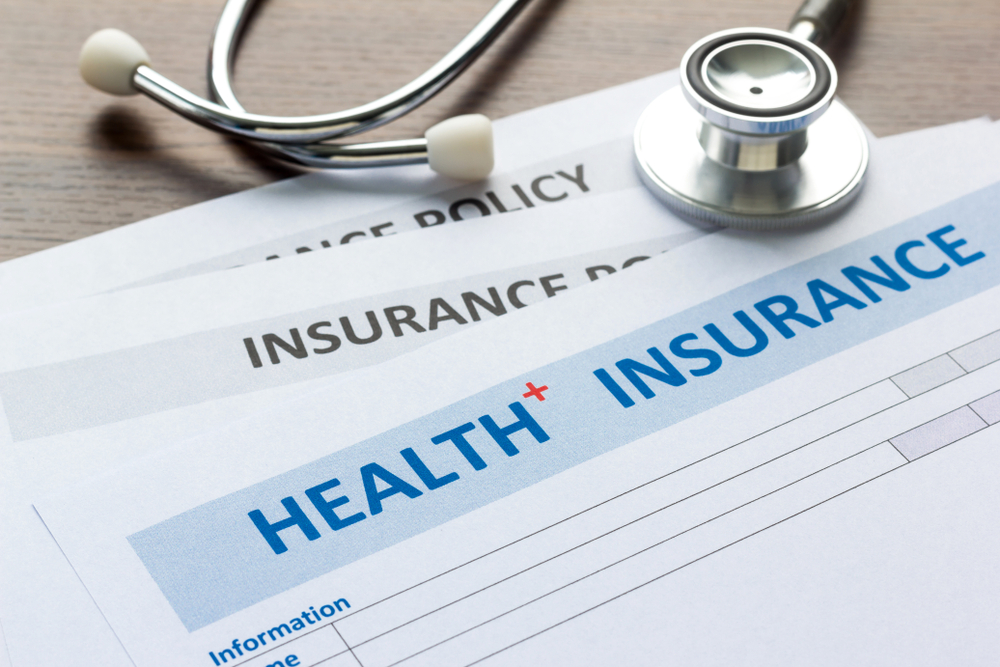 Stethoscope lying on top of health insurance policy application documents with blank forms