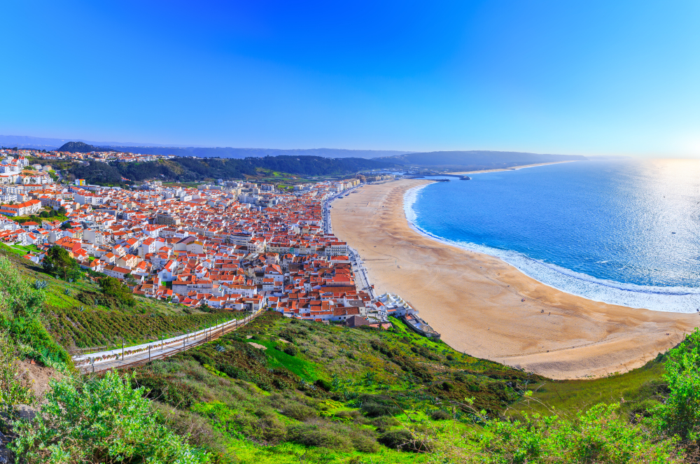 Panoramic coastline of Nazare beach with cityscape of town, and perfect sunny weather