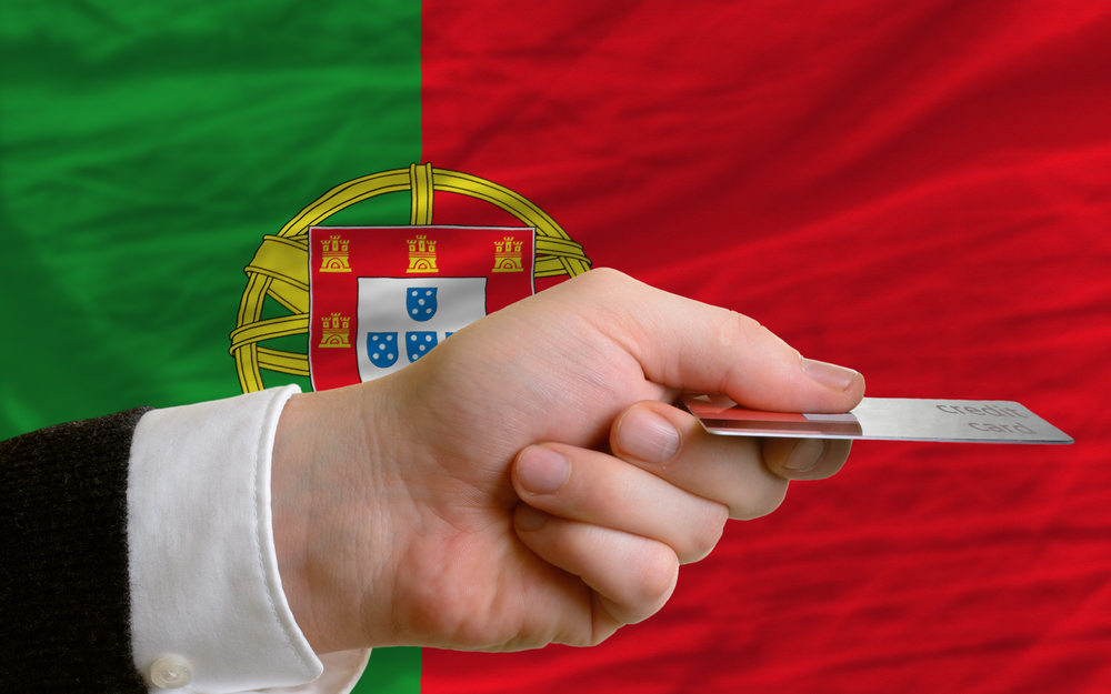 Hand holding credit card in front of Portuguese flag