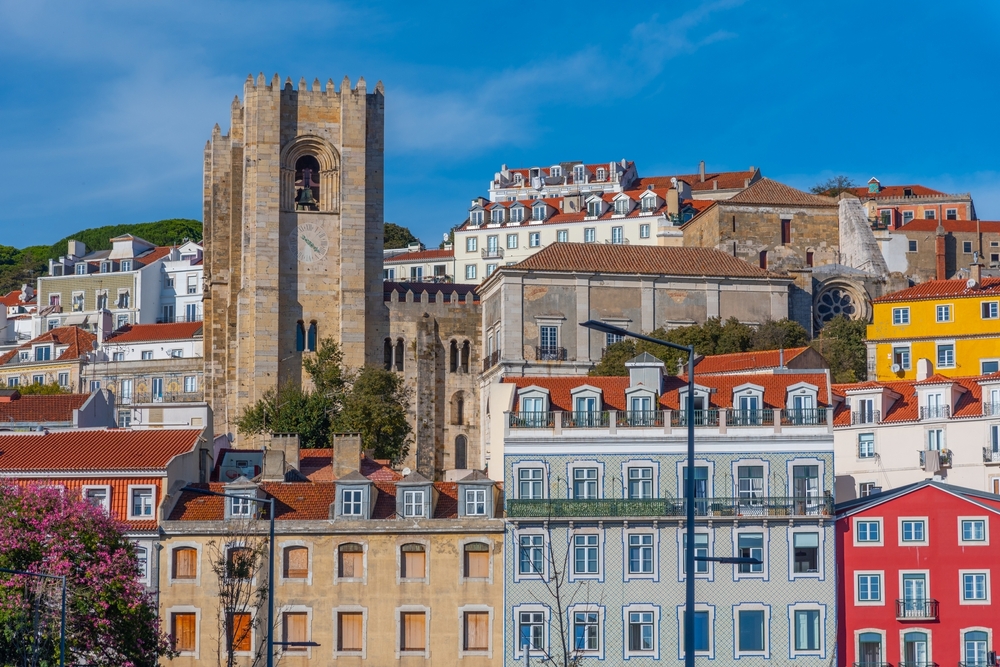 View of the Lisbon Cathedral tower rising above colorful traditional buildings