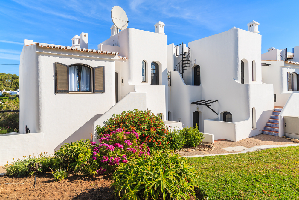 Charming traditional resort villas with spiral staircase and lush garden under sunny sky