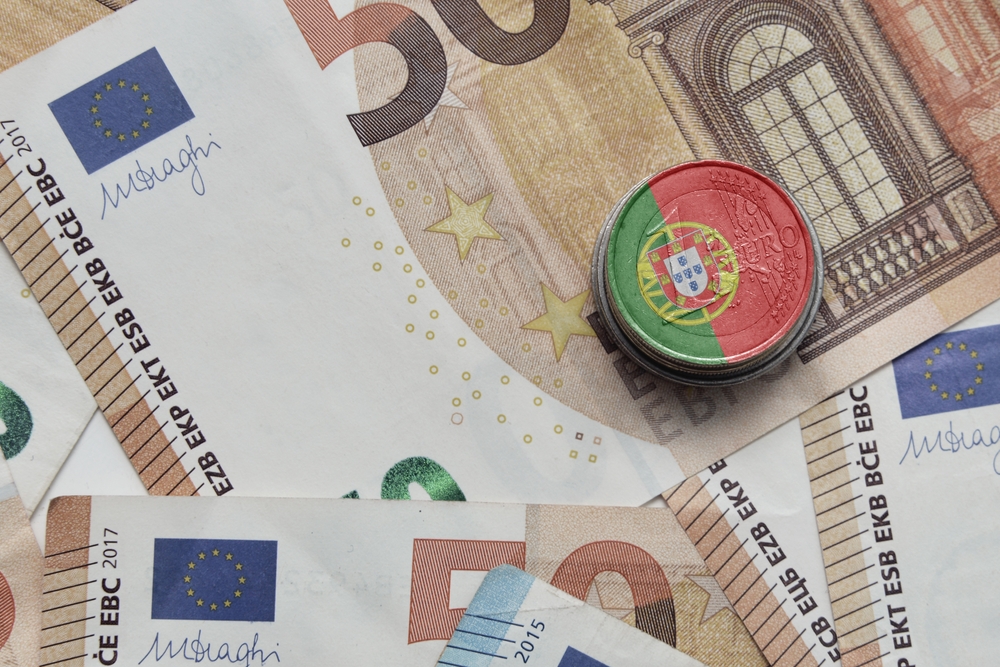 Euro notes with a pile of euro coins with a Portugal flag
