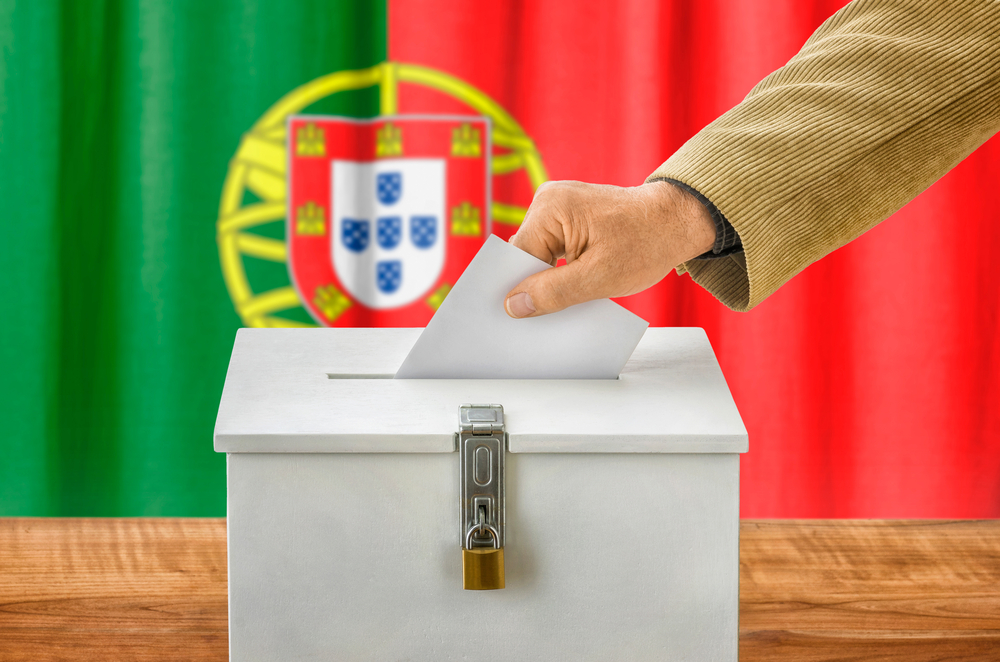 Someone casting a ballot in front of a Portugal flag