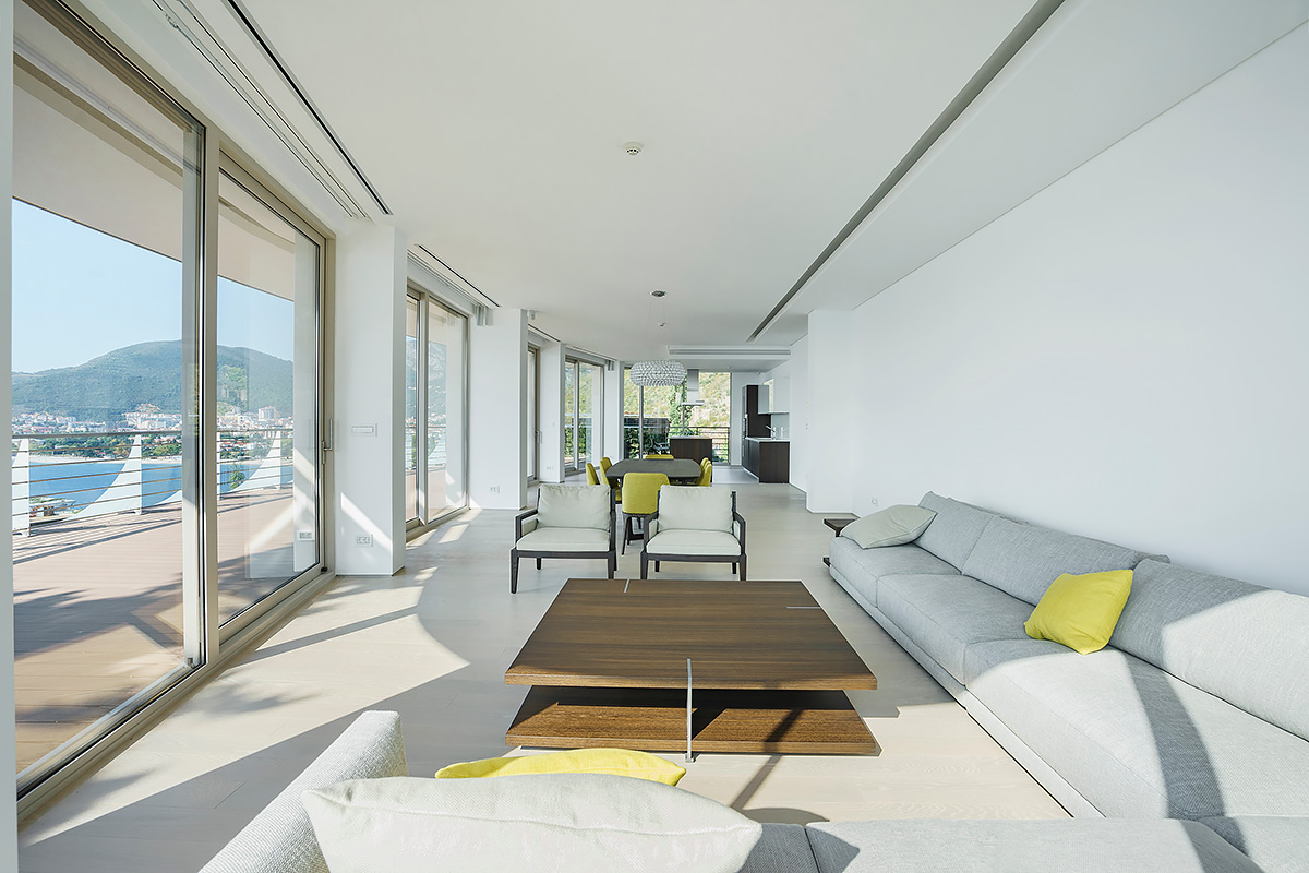 Minimalist bright living room with panoramic views and grey sectional sofa