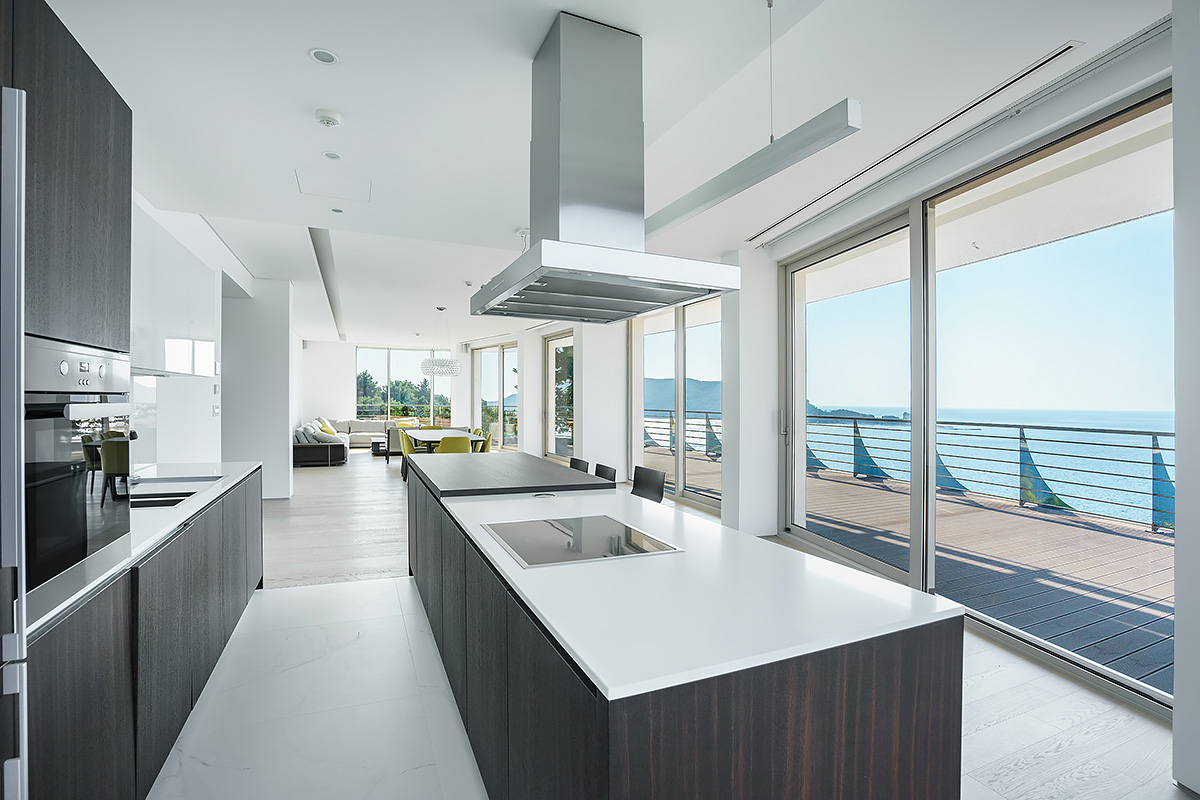 Contemporary open-plan kitchen with dark wood island and scenic balcony