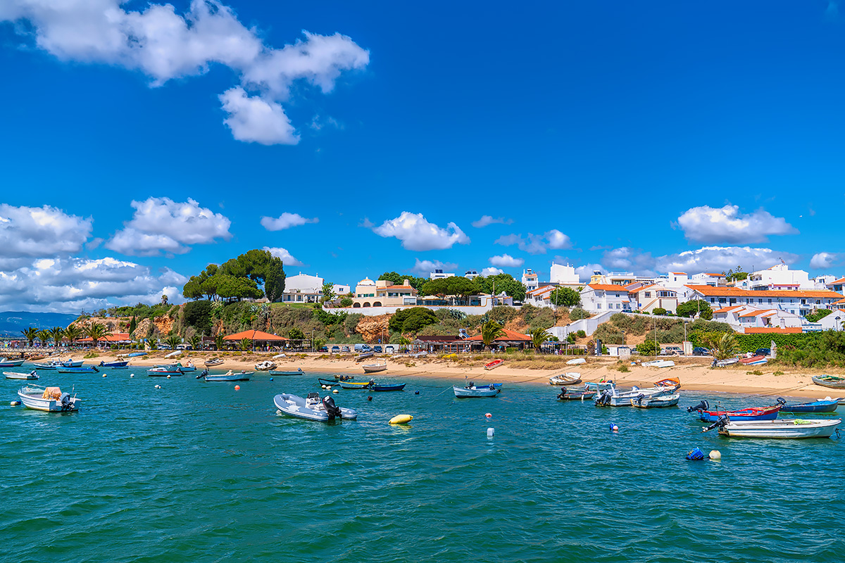 Colorful small fishing boats bob in the turquoise waters of Alvor, Portugal, on a sunny day