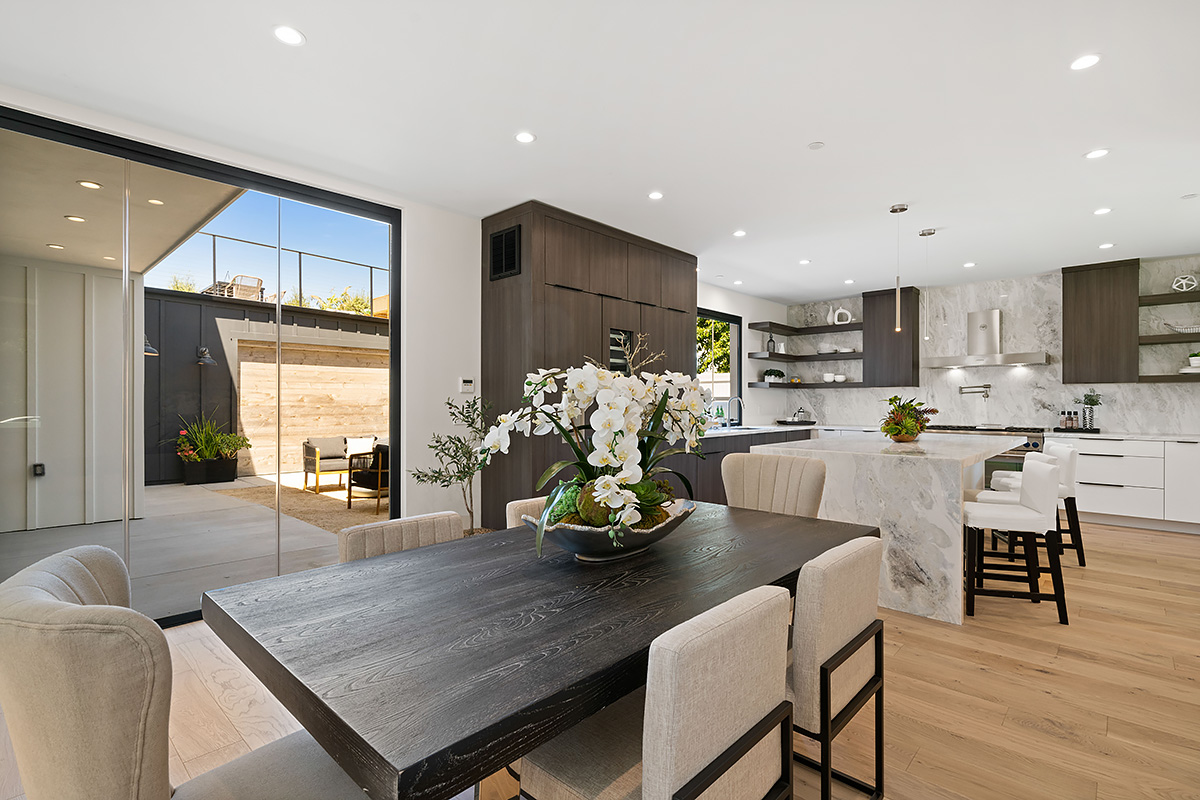 Luxury modern kitchen and dining area with marble island and open patio access