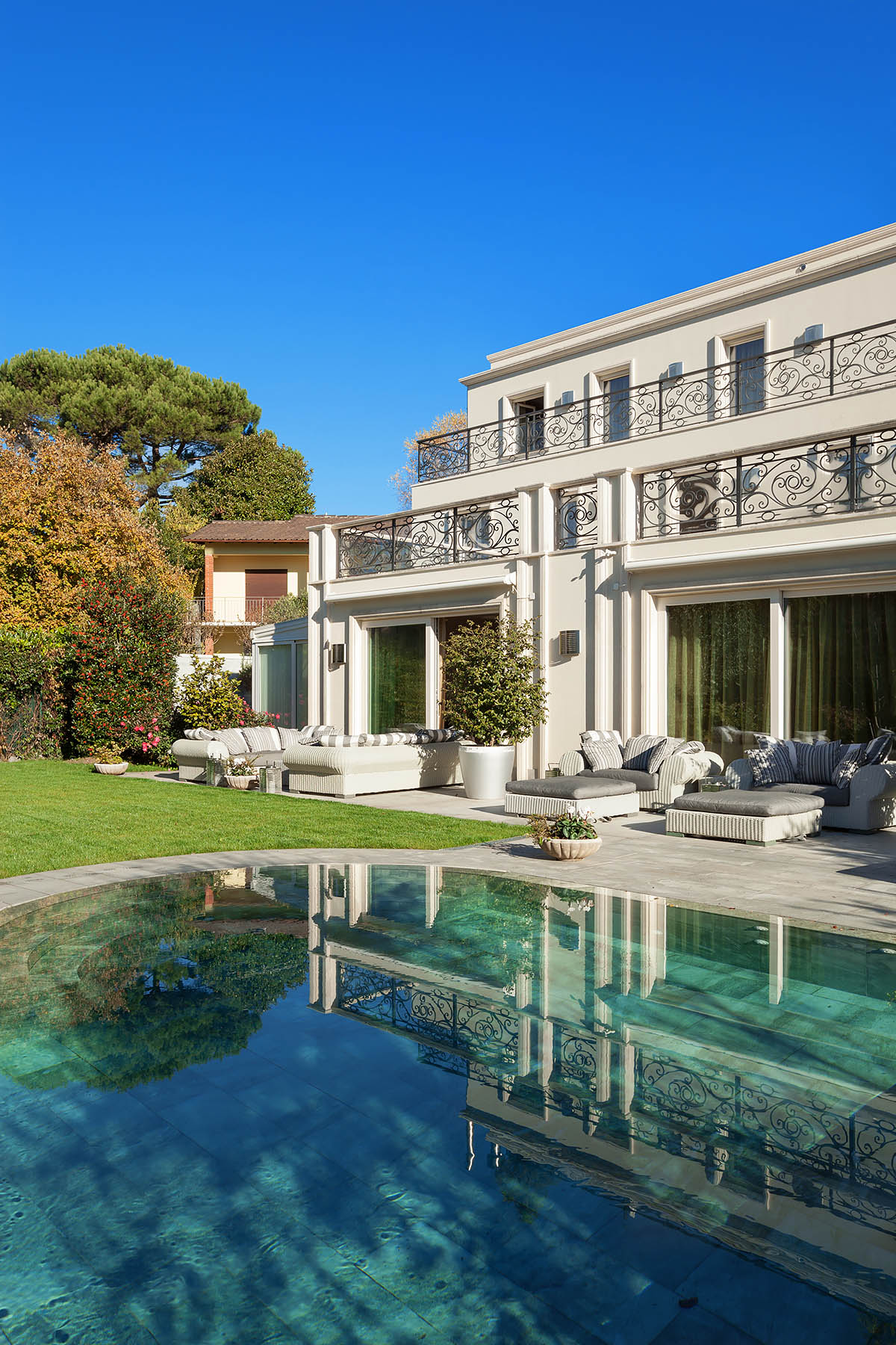 Classical luxury villa with wrought-iron balconies and reflected swimming pool