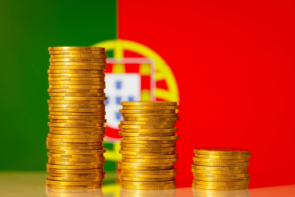 Euro coins stacked in front of a Portugal flag