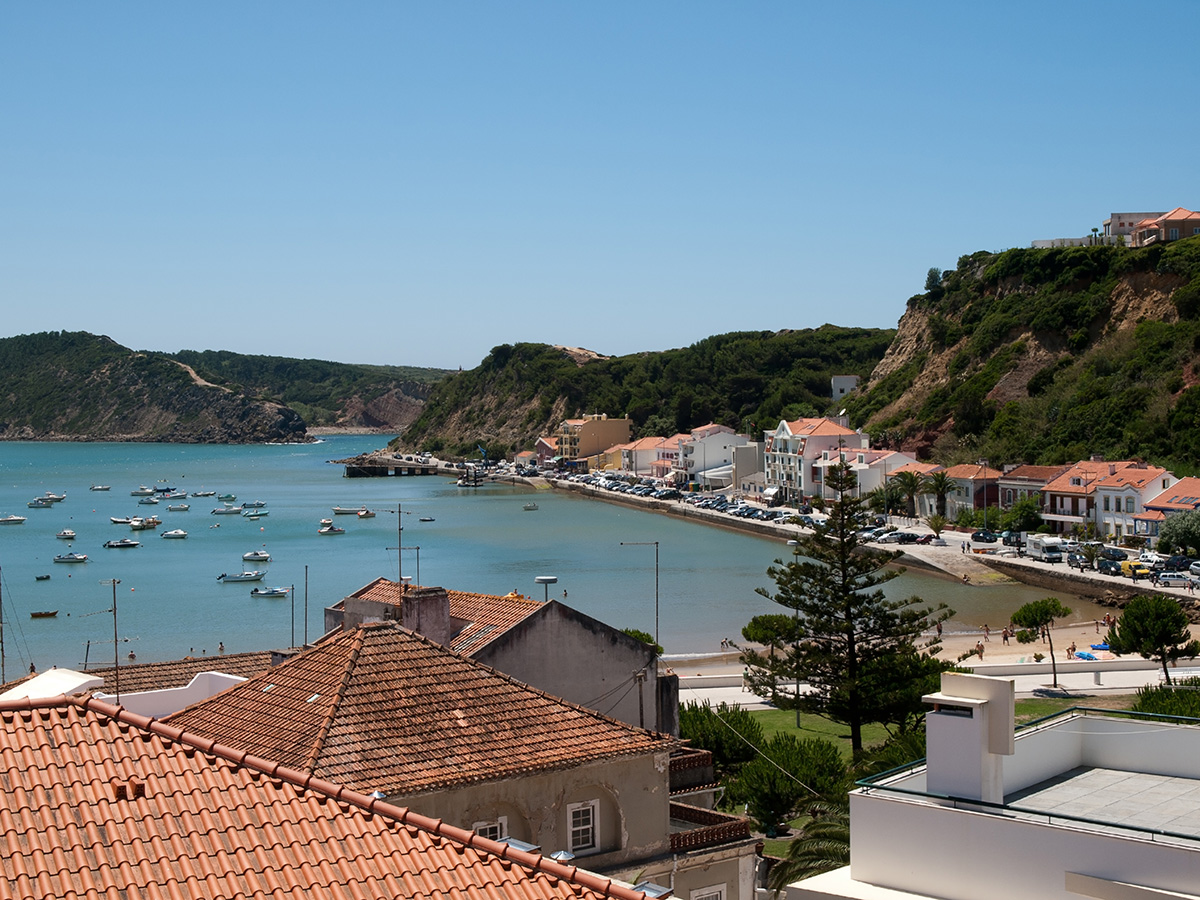 High-angle view of a sandy beach and turquoise harbour filled with small boats