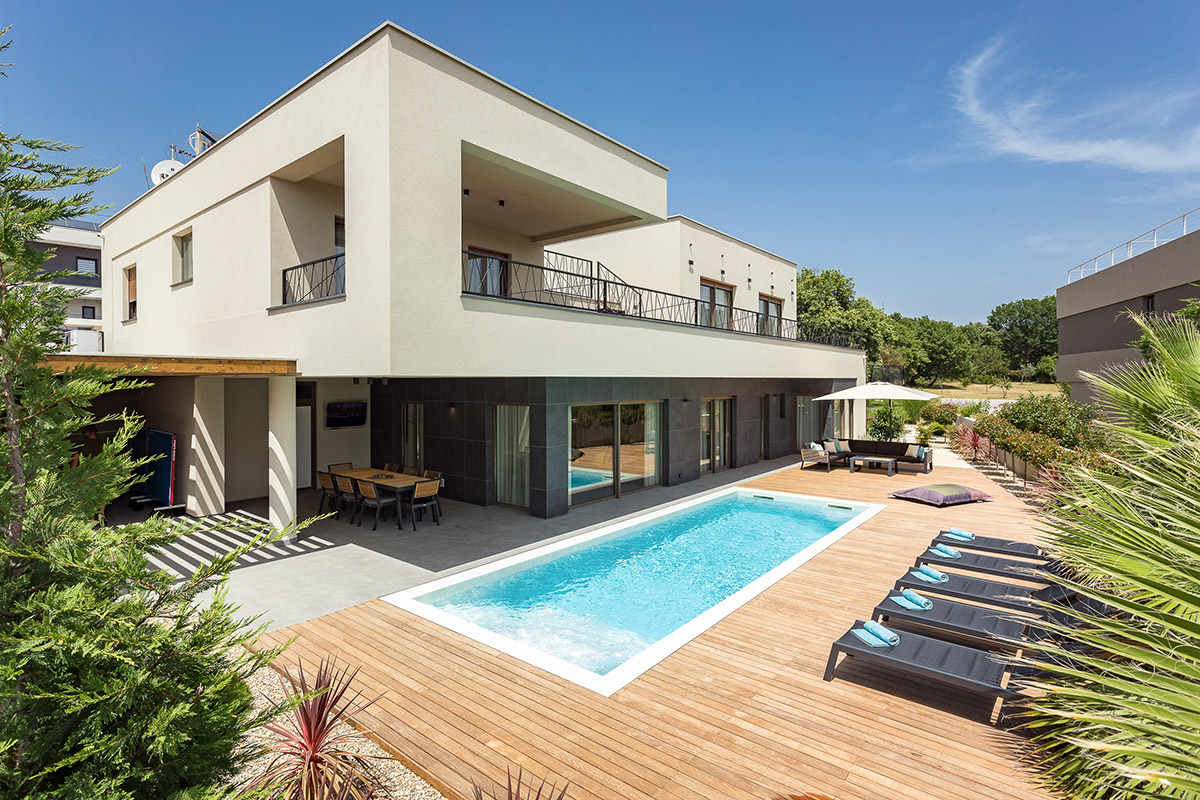 Contemporary two-story villa with a rectangular swimming pool and spacious wood deck