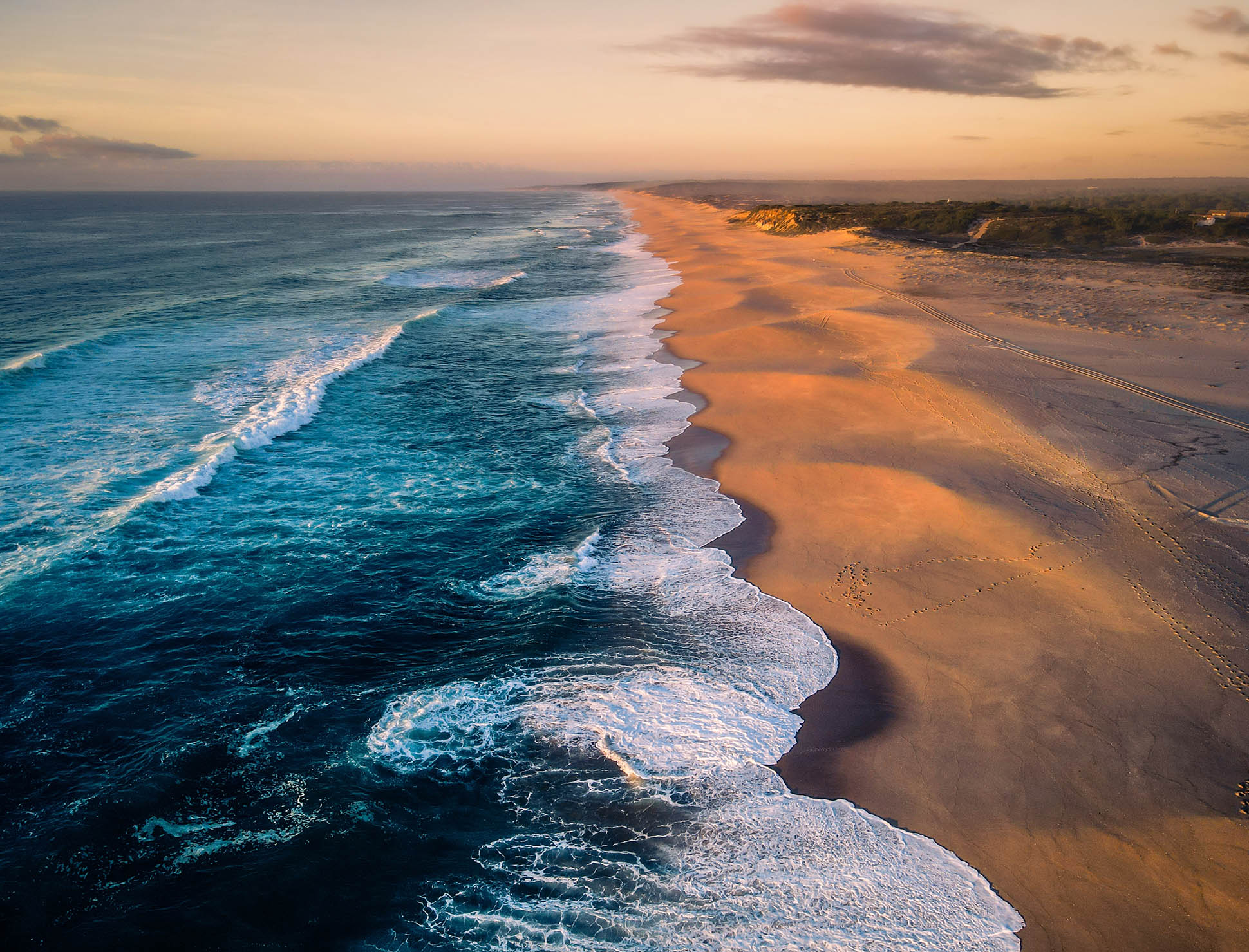 Aerial sunset view of the long, sandy Melides beach and turquoise Atlantic waves