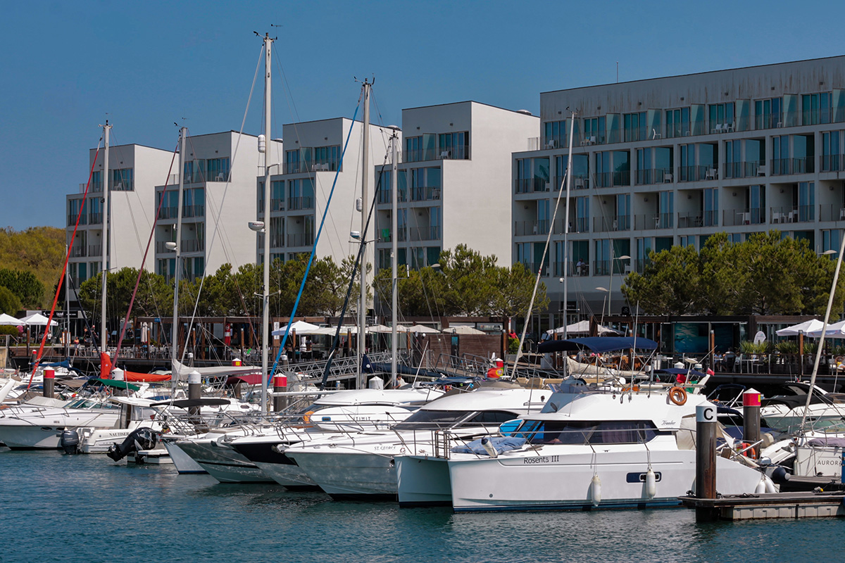 Luxury yachts and sailboats docked at a modern marina fronting sleek white apartments