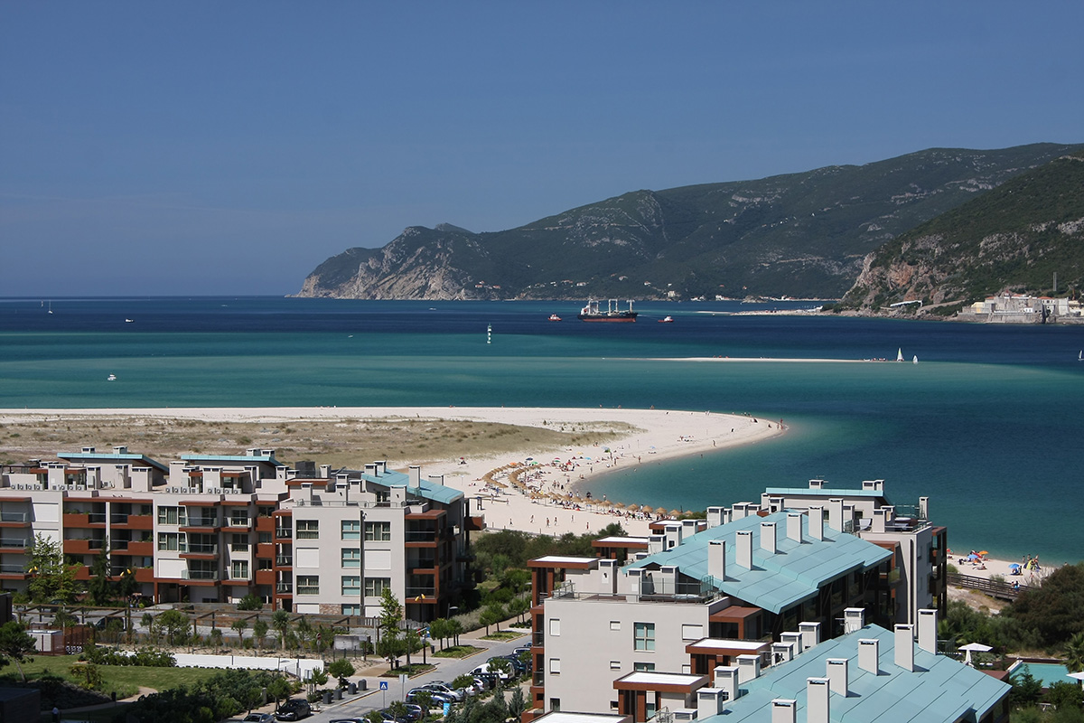 Luxury beachfront apartments overlooking a white sand bar and turquoise bay with mountains