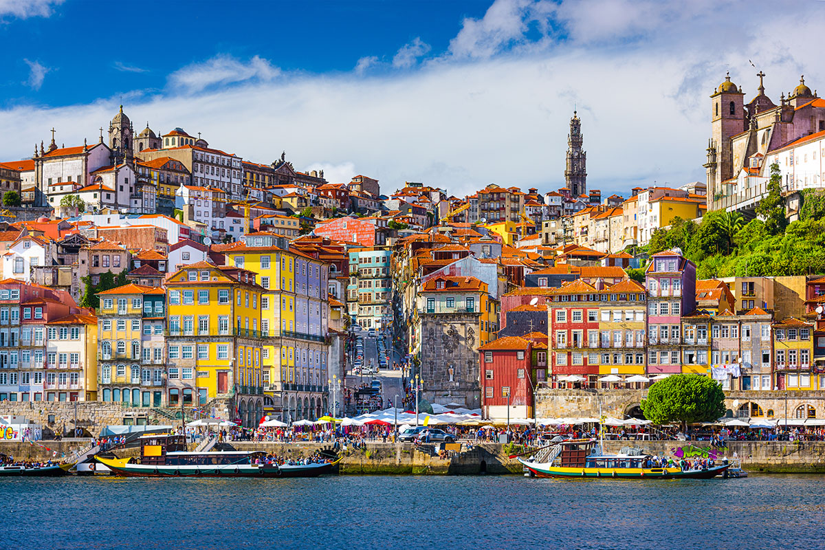 Colorful Rabelo boats docked along the vibrant, terraced hillsides of Porto's Ribeira district