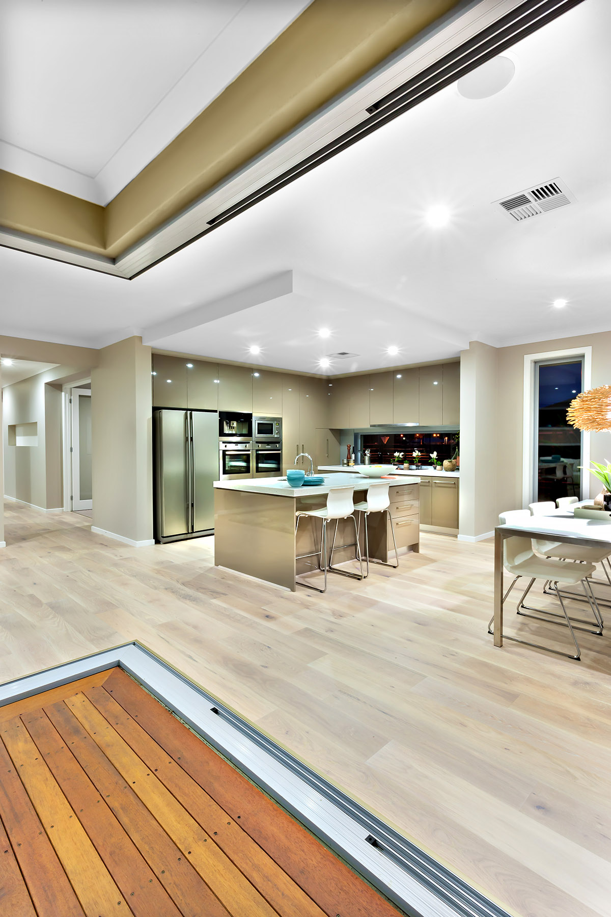 Modern open-concept kitchen with neutral tones, island seating, and light wood flooring