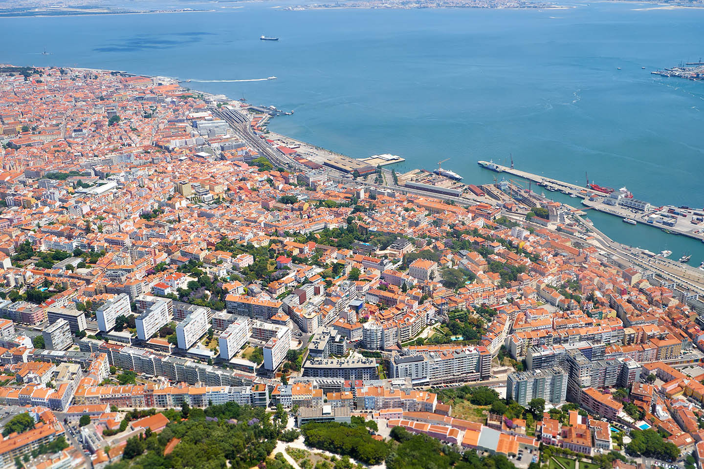 Aerial panorama of Lisbon's coastline, featuring the Tagus River and industrial port docks