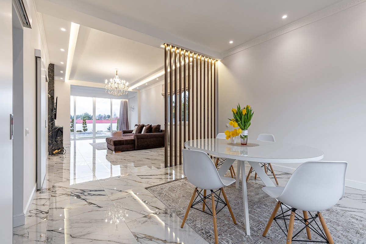 Modern living room with marble floors, a wooden slat room divider, and a crystal chandelier