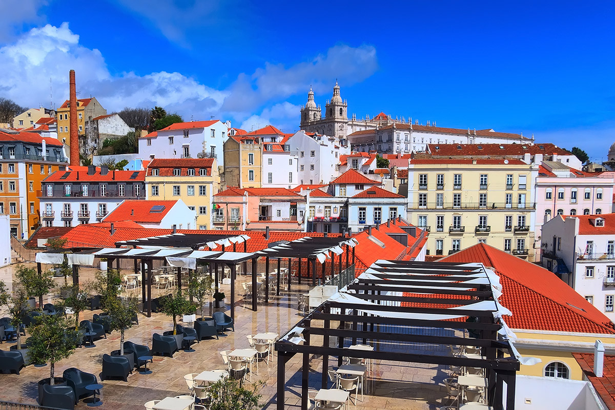 Outdoor terrace with black pergolas overlooking red roofs and a historic cathedral in Lisbon