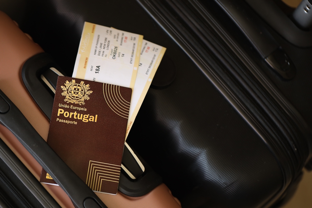 Portugal passport with plane ticket on top of suitcase