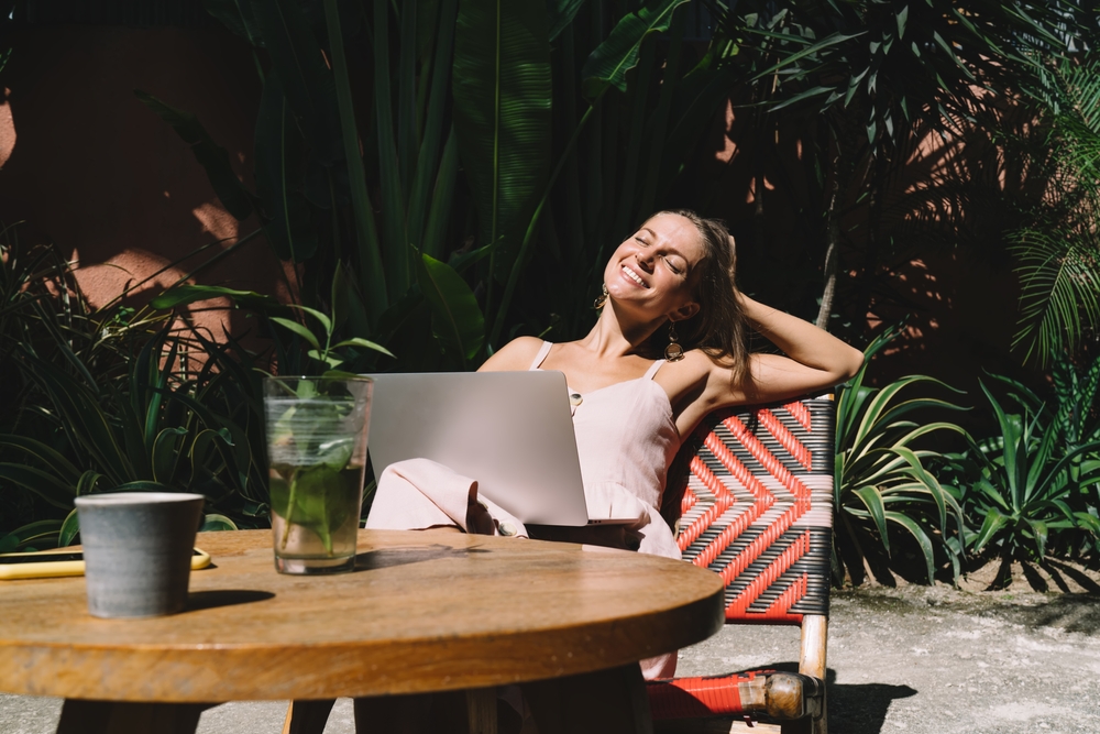 Digital nomad smiling and working in the sun