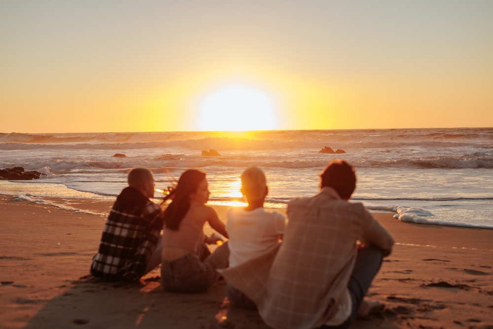 Group of friends sat on a beach in Portugal at sunset