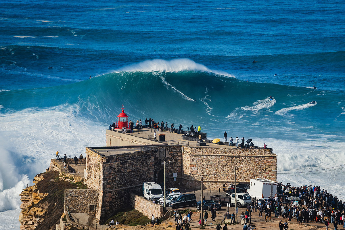 Surfer on a massive wave by the Nazaré lighthouse at Fort of São Miguel Arcanjo