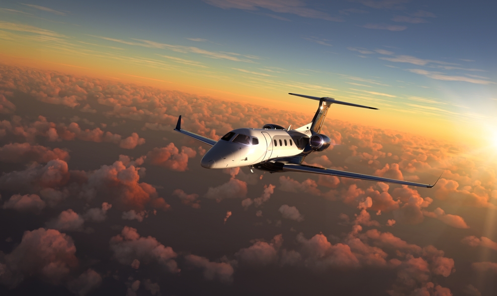 Private jet flying through sunset