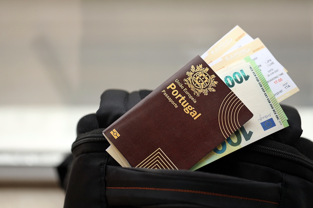 Portugal Passport full of money on top of travel bag