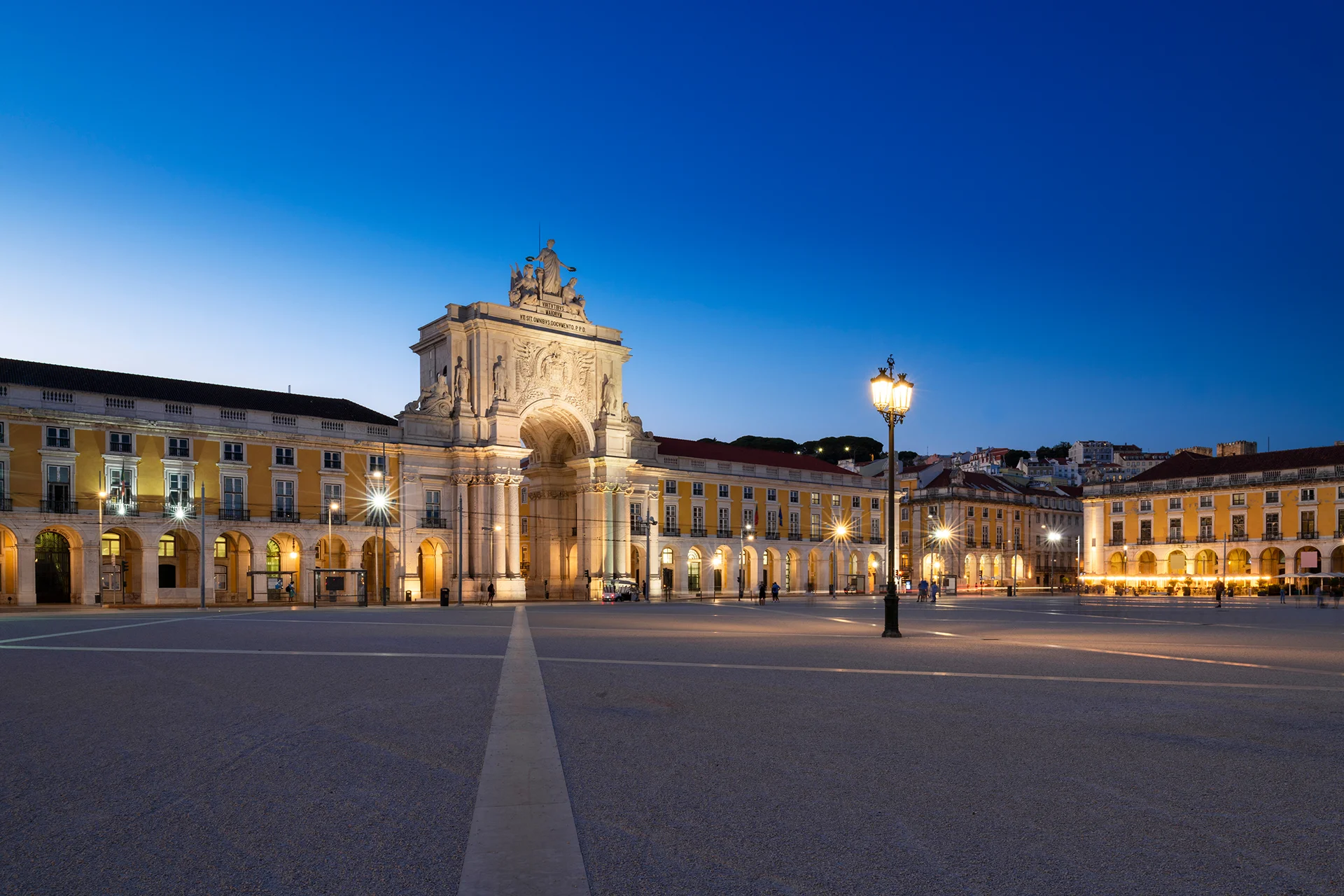 The Rua Augusta Arch at twilight in Lisbon's Praça do Comércio, lit under a deep blue sky