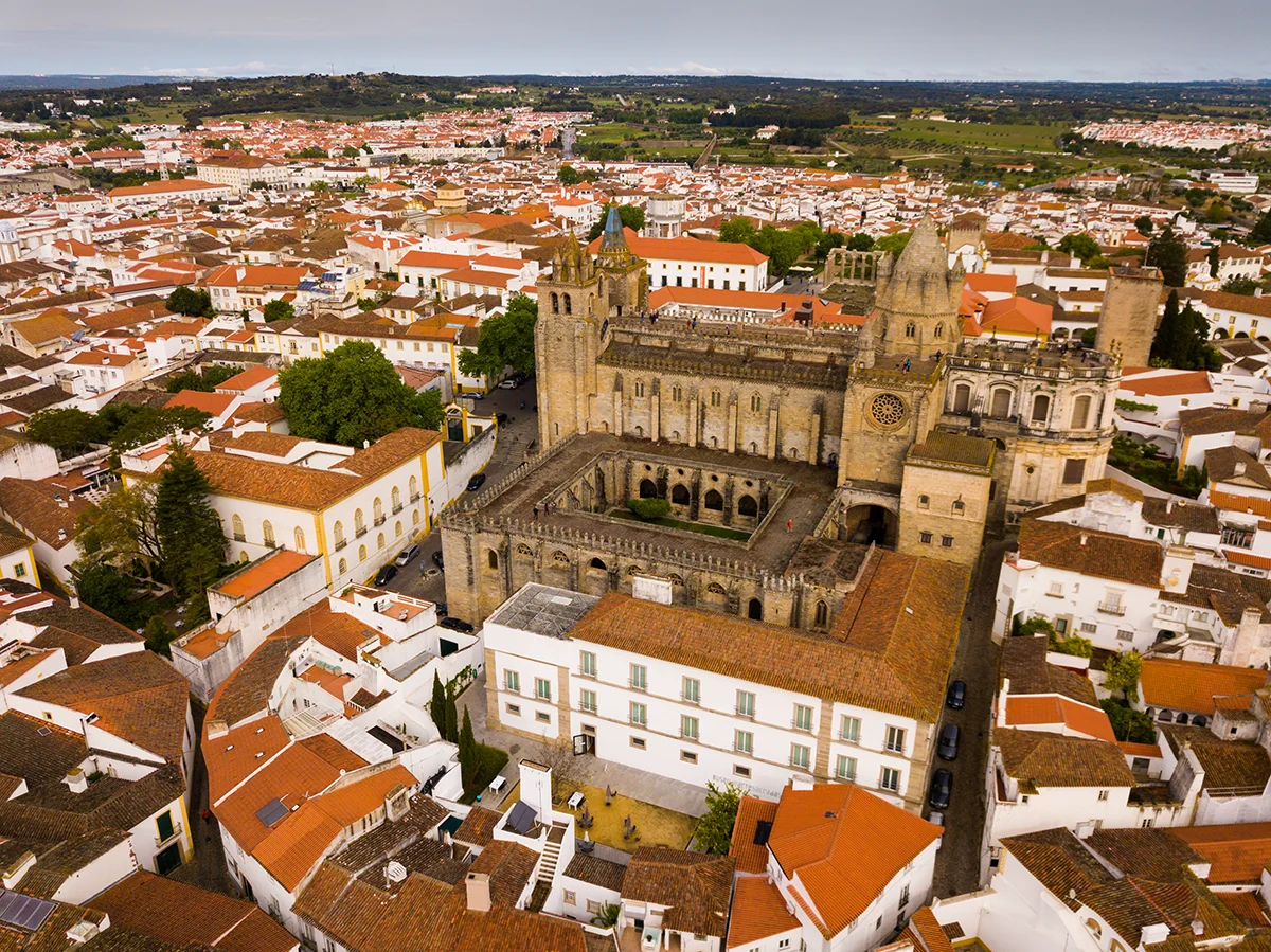 The historic stone cathedral and courtyard stand out amidst a sea of orange rooftops