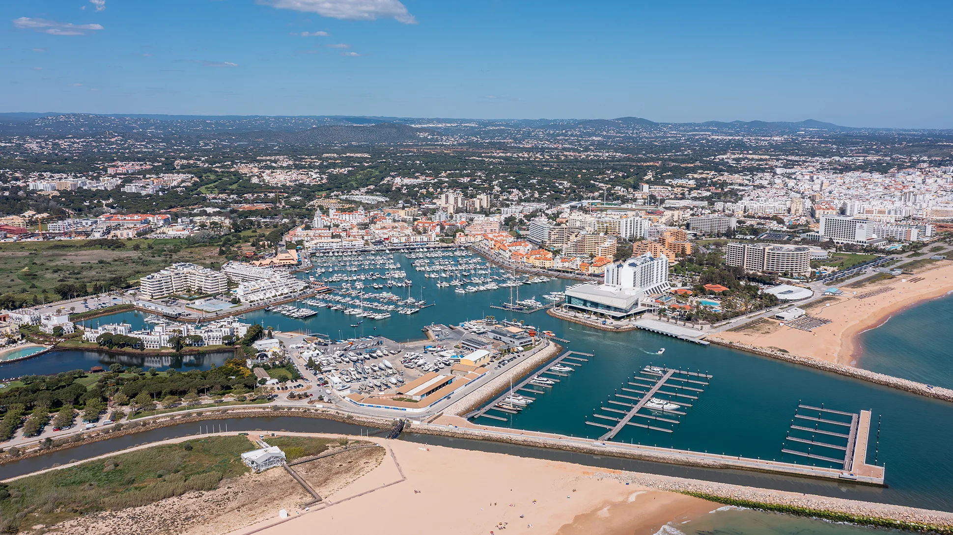 Waterways of a massive coastal marina filled with boats stretch toward the horizon