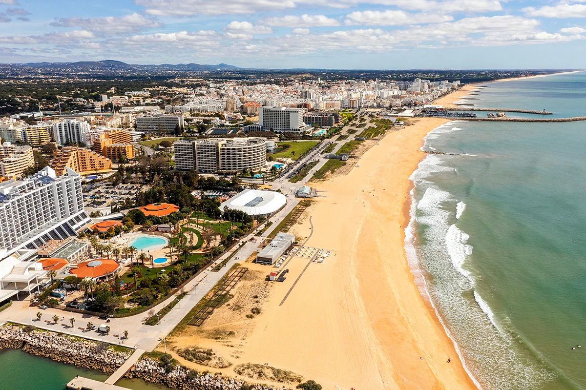 A sweeping view of a vast golden sand beach lined with luxury beachfront resorts
