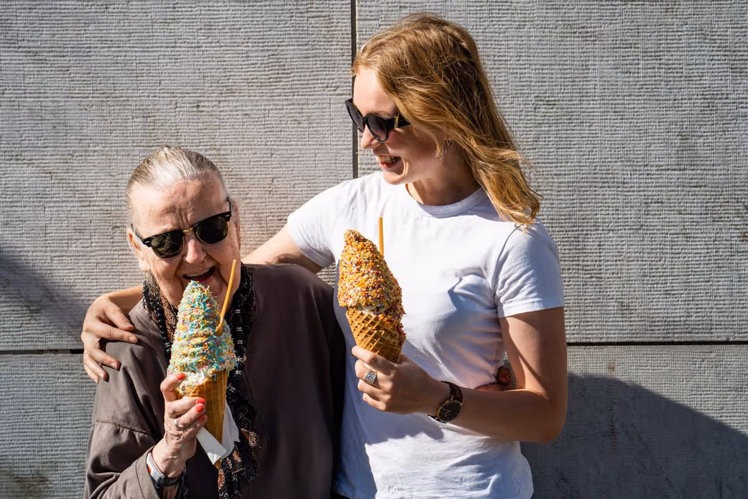 One old person and one young eating ice cream together and laughing