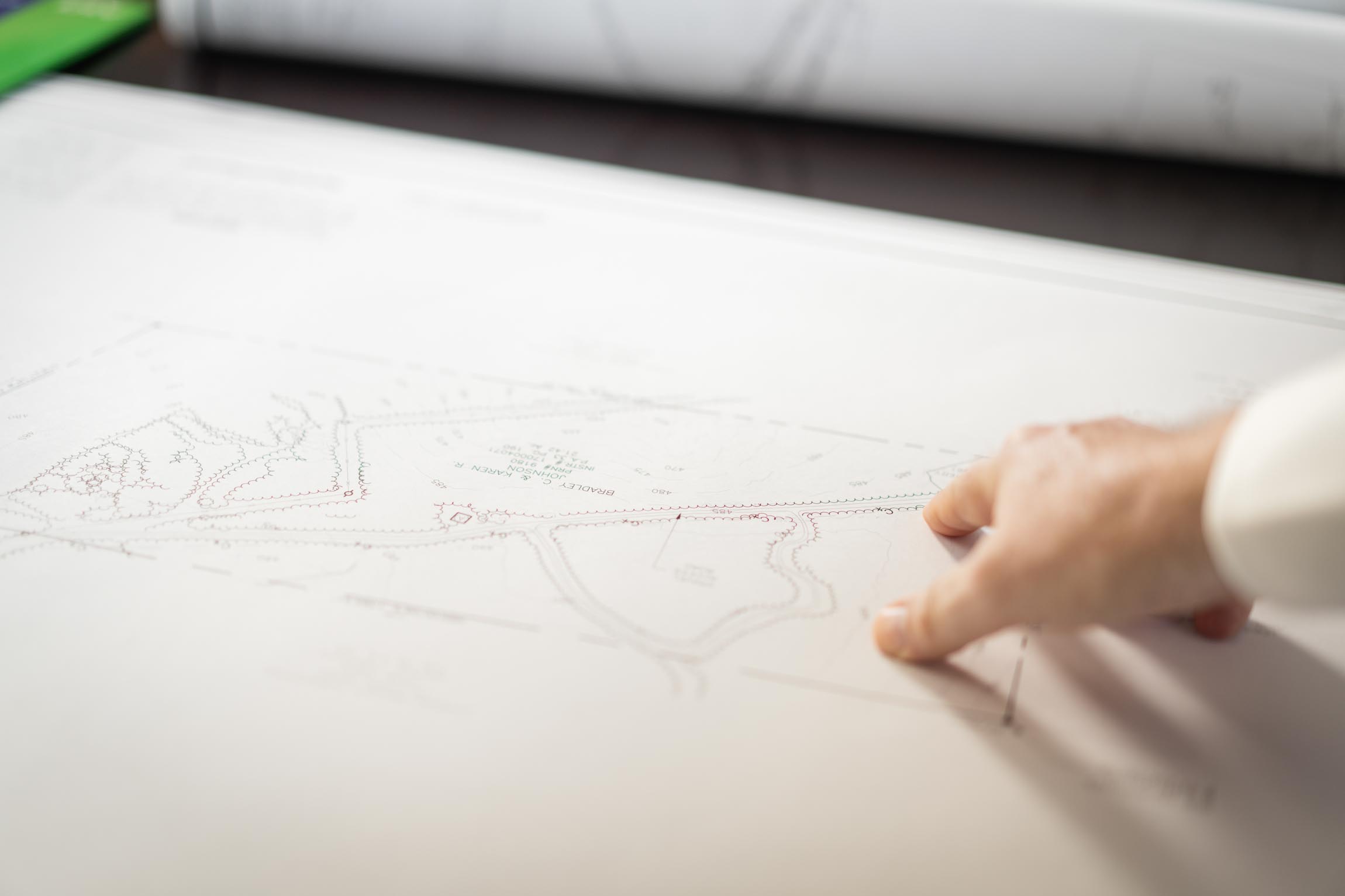 Close-up of a hand pointing to details on a technical blueprint or architectural plan.