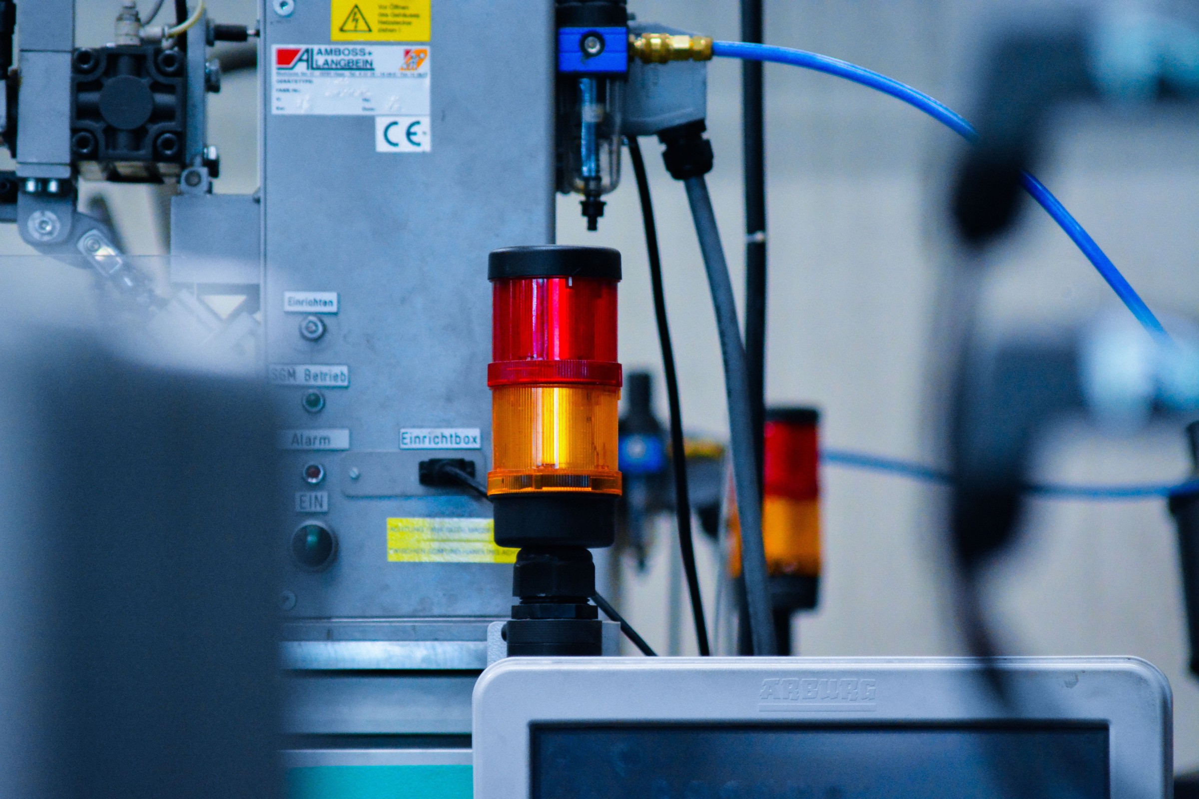Close-up of industrial machinery with cables and a red-and-yellow signal light.