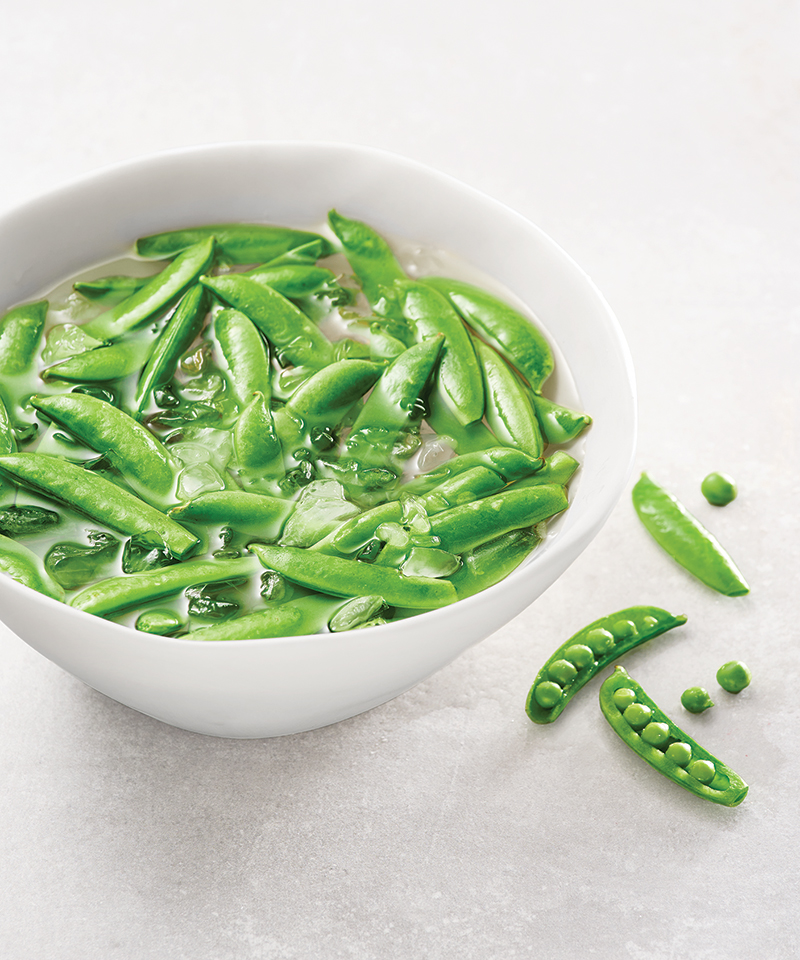 Bright green snap peas in a howl of ice water.