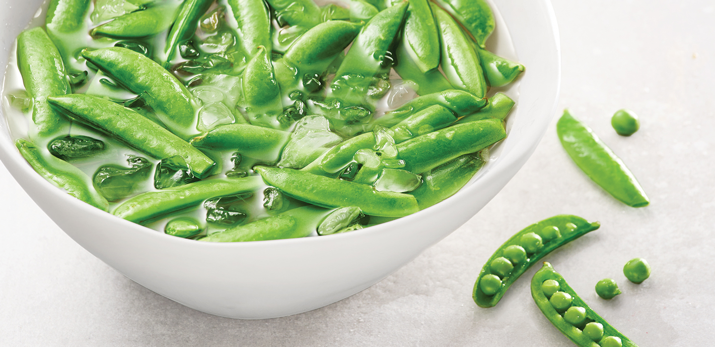 Bright green snap peas in a howl of ice water.