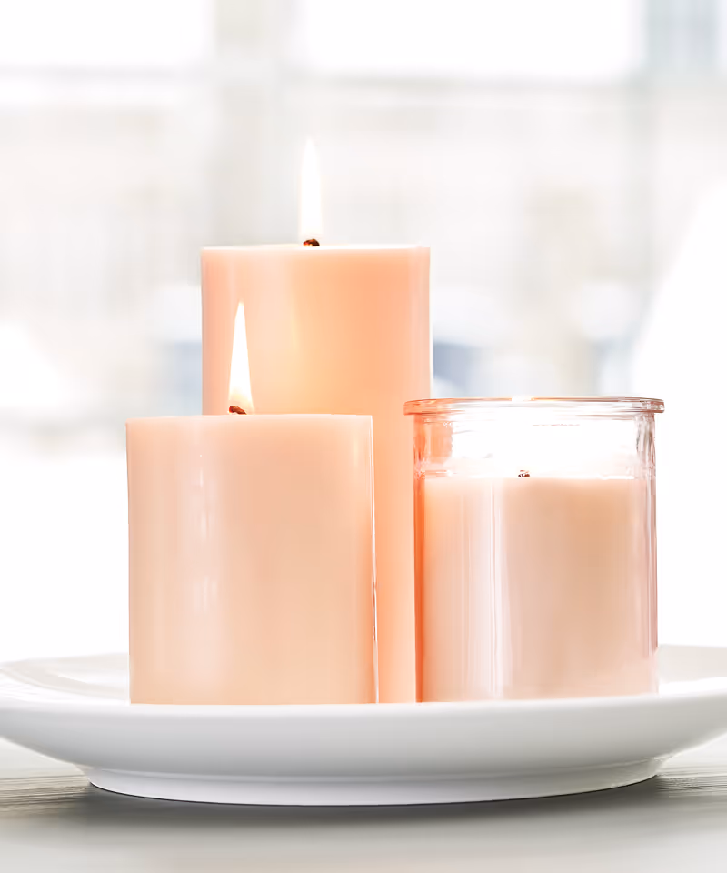 Three lighted pink candles of varying heights sitting on a white tray.