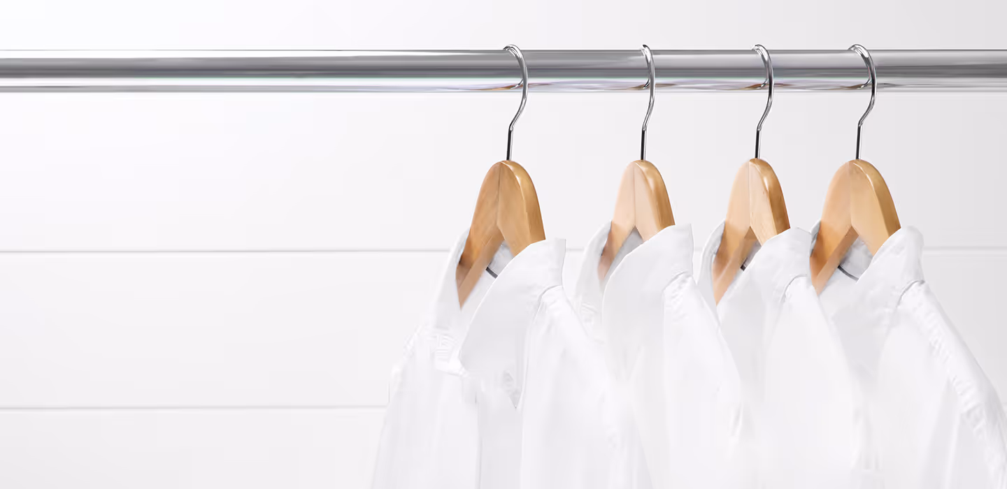 Four hanging white collared shirts.