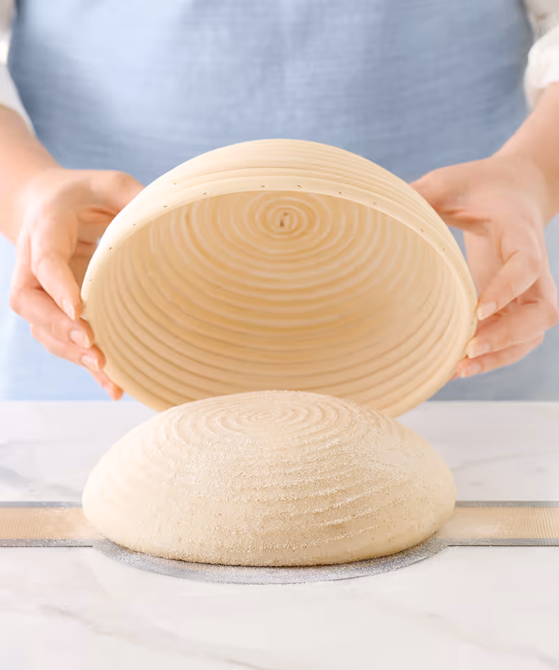 A dough ball being placed on a countertop from a bowl.