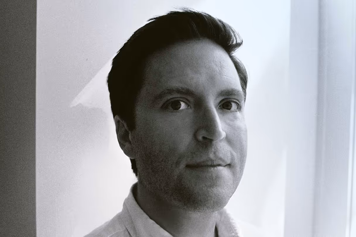 Black and white portrait of a man with short dark hair, looking toward the camera.