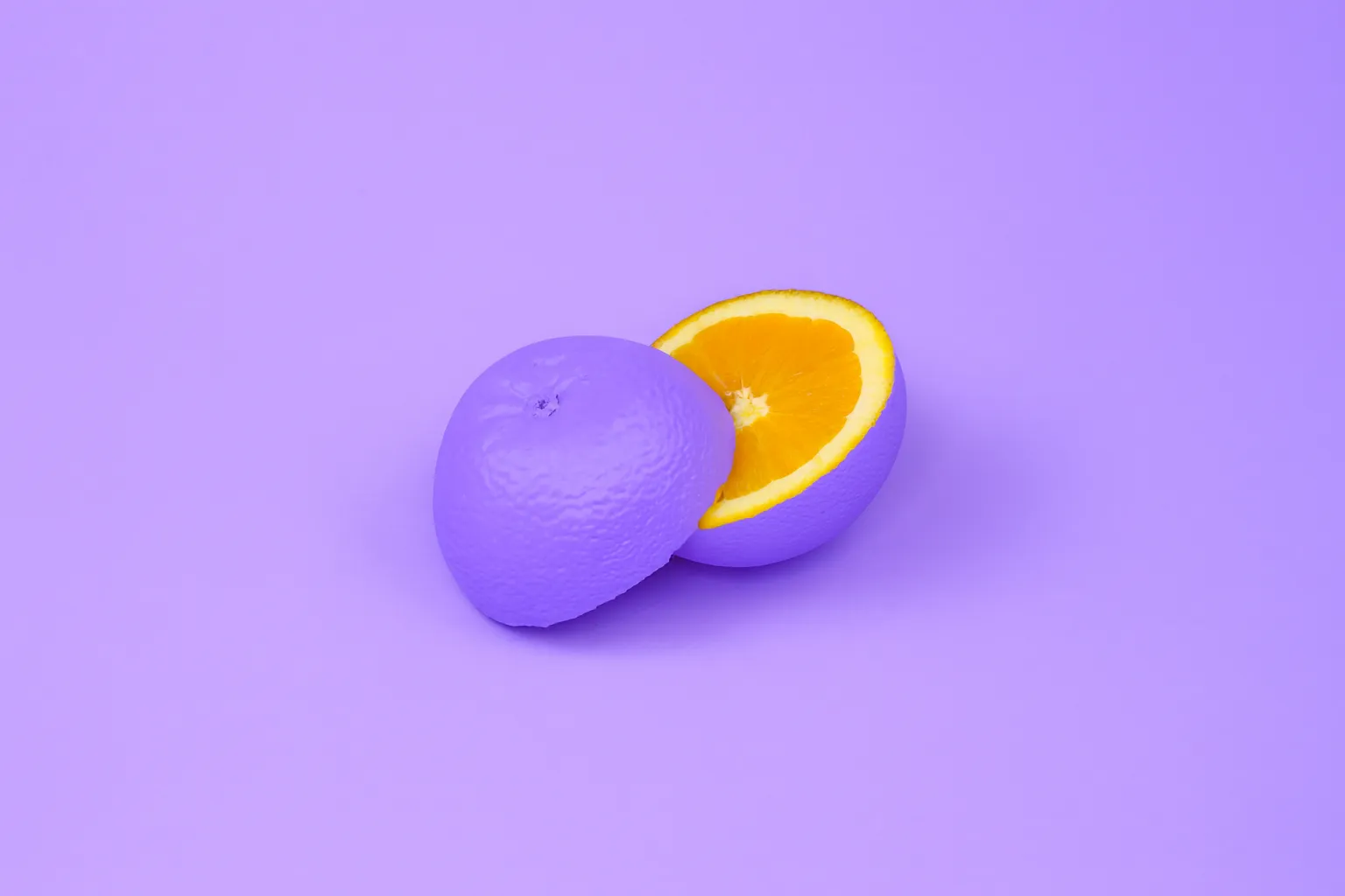 Une orange coupée en deux, entièrement peinte en violet sur fond violet, seule la chair restée orange