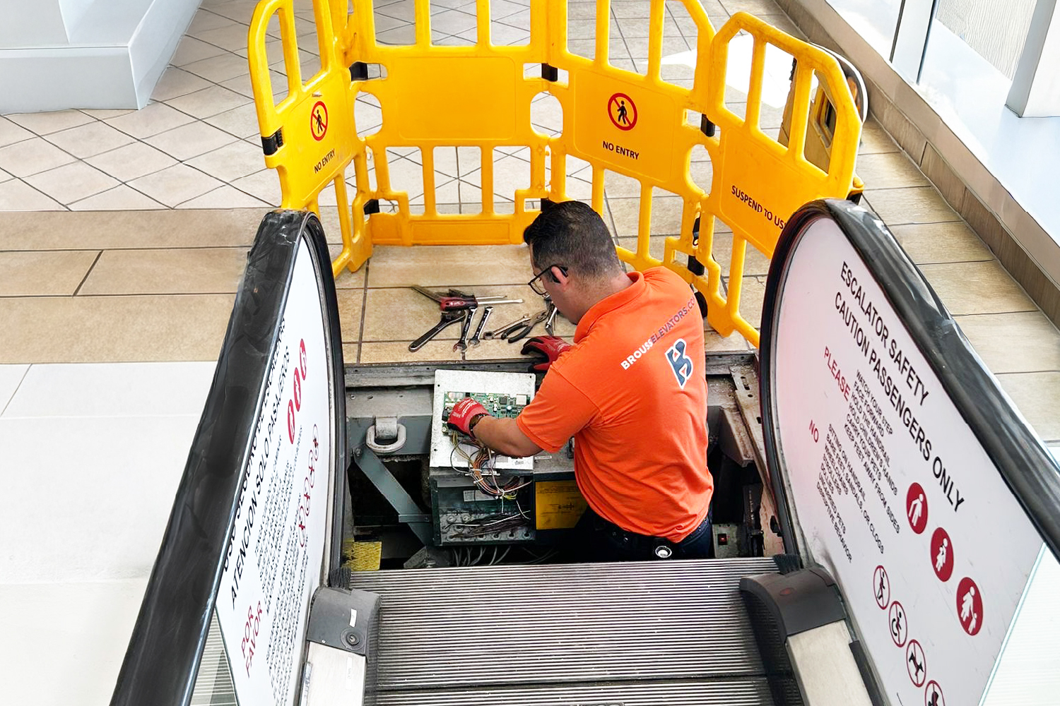 Brouss technician performing preventive maintenance on an escalator