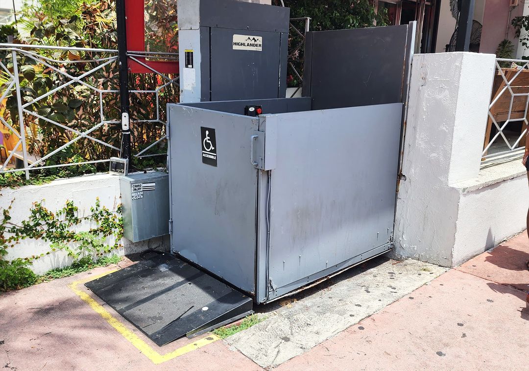 Brouss technician servicing the base of an outdoor ADA platform lift