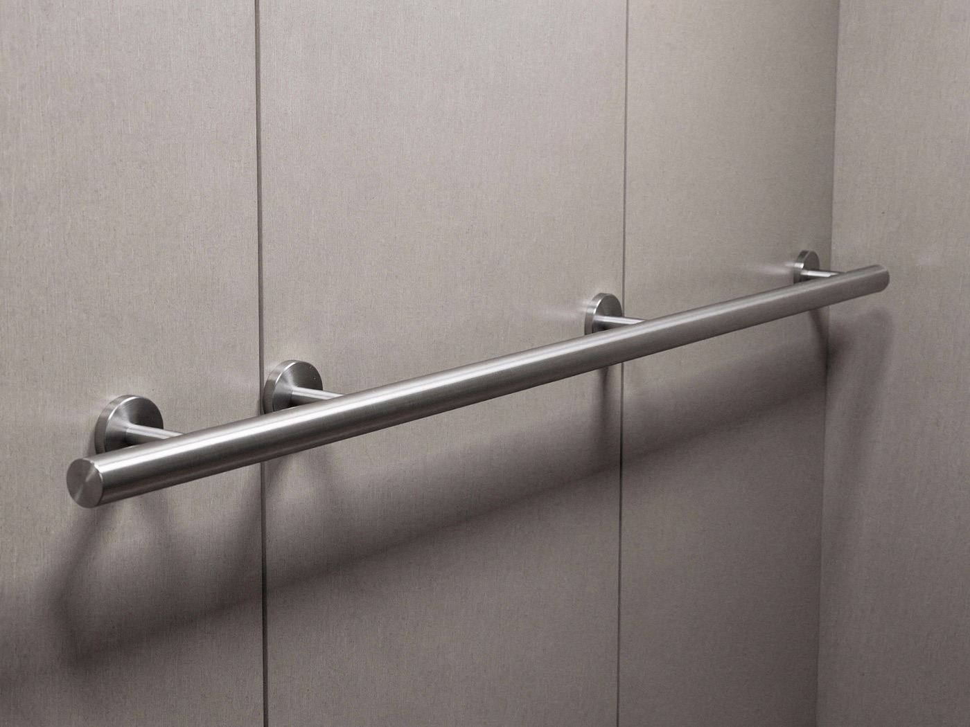 Round 1.5 inch brushed stainless steel tube handrail on standoff brackets in an elevator cab
