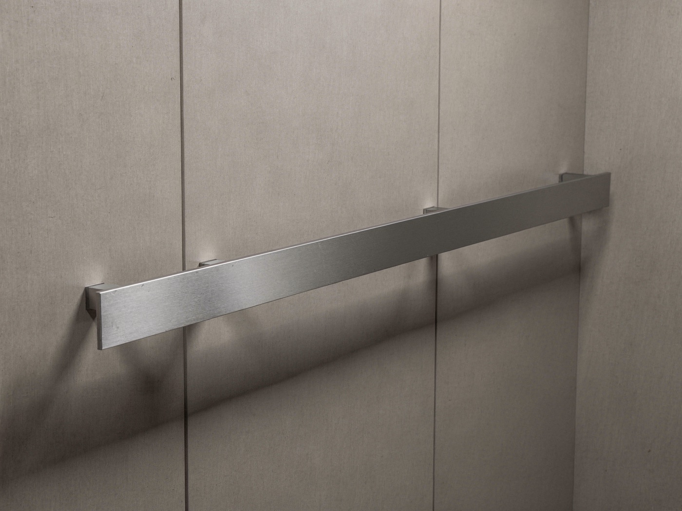 Flat 2 inch brushed stainless steel bar handrail on an elevator cab wall