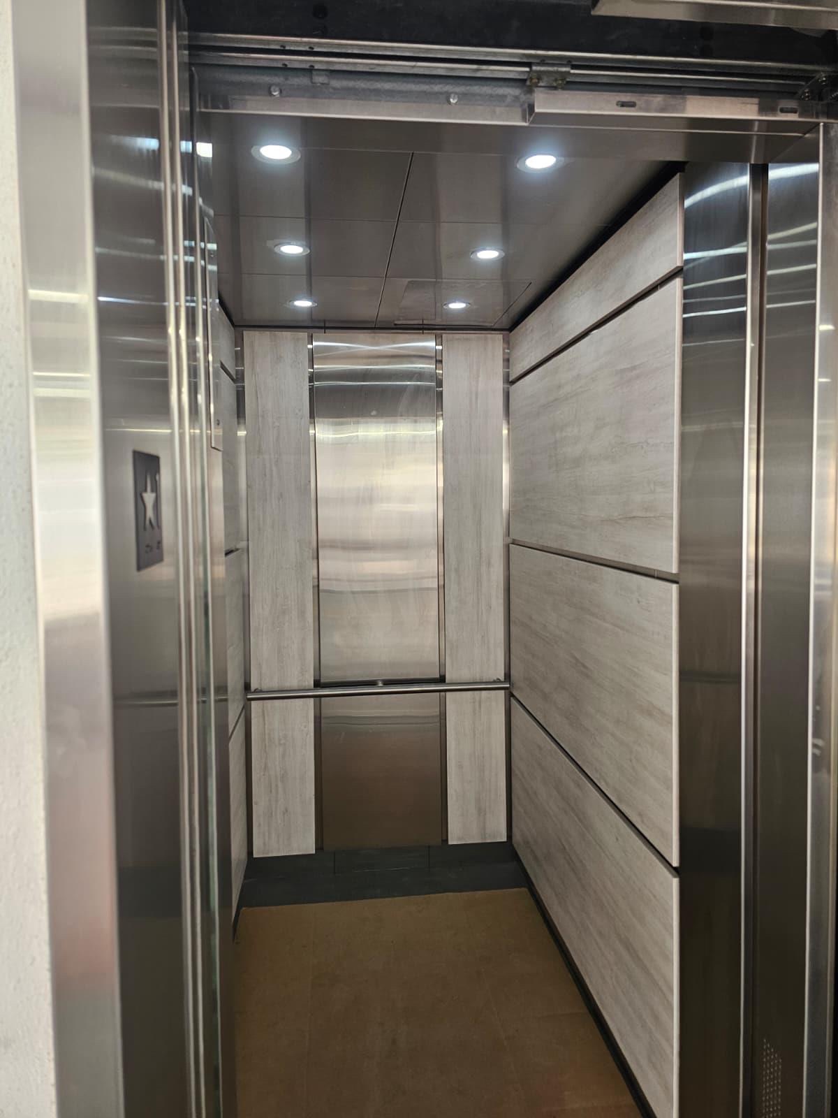 Interior of the new elevator cab with light wood panels and stainless accents at 652 NE Building