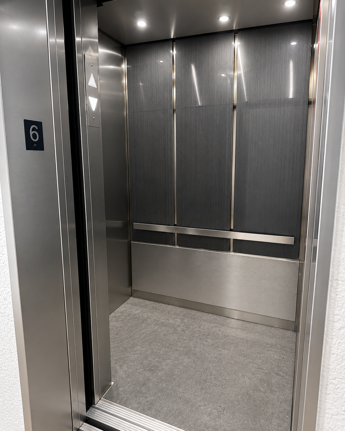Renovated elevator cab interior with gray brushed panels, stainless steel handrail and new flooring at Fairways Royale in Hallandale Beach